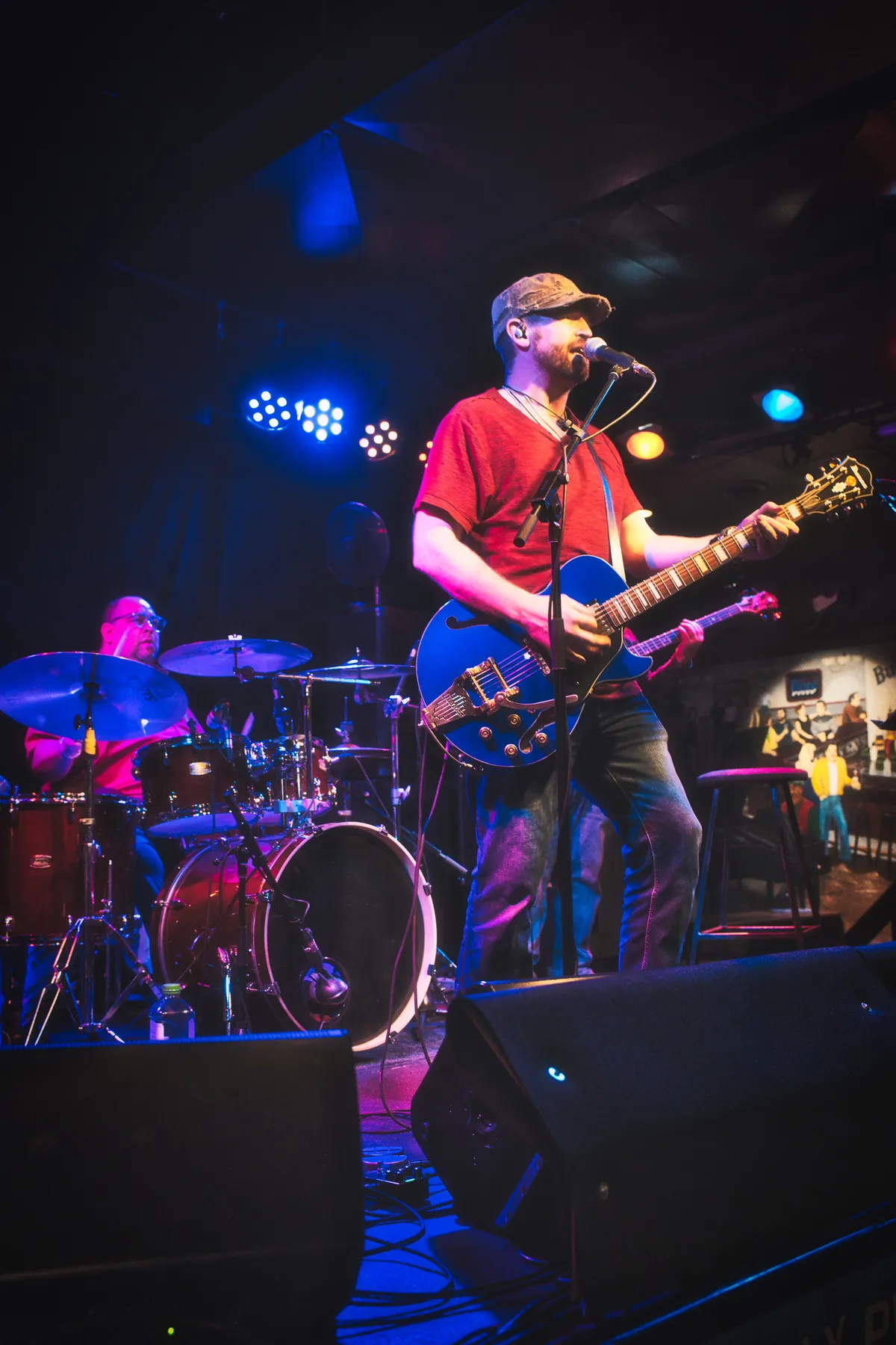 Michael Lander on stage in a red shirt playing a blue electric guitar