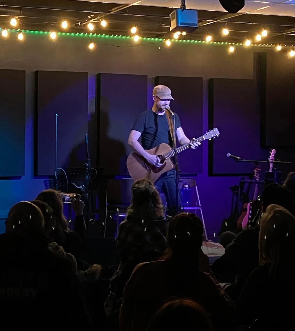 Michael Lander singing and playing acoustic guitar in front of a seated audience
